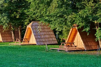 a group of wooden shelters sitting under a tree at Glamping Village - Speleo Camp in Logatec