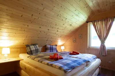 a bedroom with a bed in a wooden cabin at Holiday Home- Mountain Lodge Gorjuše Pokljuka Bohinj in Koprivnik v Bohinju