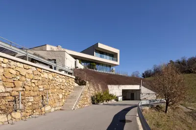 a building with a stone wall next to a road at Apartmaji Guerila in Ajdovščina