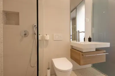 a white bathroom with a toilet and a sink at Apartmaji Guerila in Ajdovščina