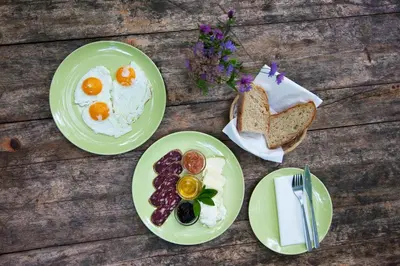 three plates of eggs and bread on a wooden table at Forest Camping Mozirje in Mozirje