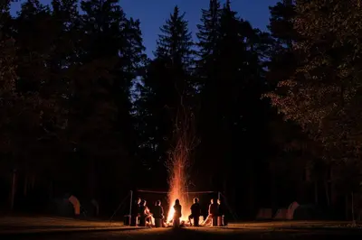 a group of people standing around a fire at night at Forest Camping Mozirje in Mozirje