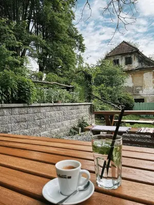 a cup of coffee and a glass of water on a wooden table at Vintage tent at the Lovsin Estate in Metlika