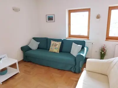 a living room with a blue couch and two windows at Apartment Jalps 1 in beautiful Bohinjska Bistrica in Bohinj