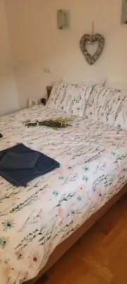 a bed with a floral comforter and a heart decoration on the wall at Apartment Jalps 1 in beautiful Bohinjska Bistrica in Bohinj