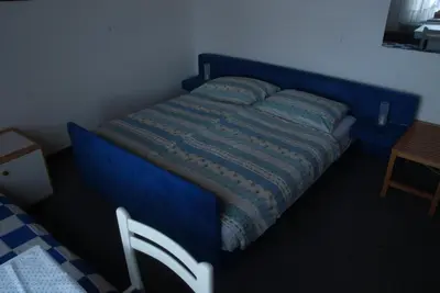 a blue bed in a room with a chair at Guest Accomodation Škerlak in Moravske Toplice