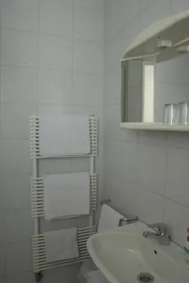 a white bathroom with a sink and a towel rack at Guest Accomodation Škerlak in Moravske Toplice