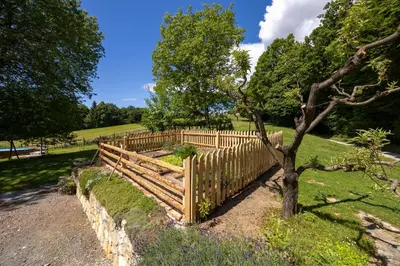 a wooden fence next to a tree in a field at Tourist Farm Rajšp in Benedikt v Slovenskih Goricah
