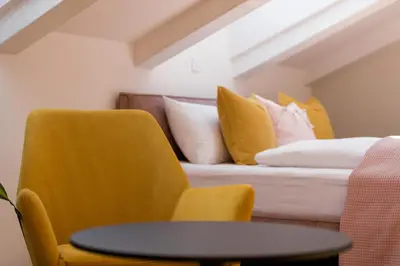 a bedroom with a yellow chair and a bed with pillows at La Villa Ljubljana in Ljubljana