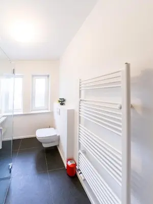 a white bathroom with a toilet and a window at Kamr’ca in Ljubljana