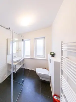 a white bathroom with a toilet and a sink at Kamr’ca in Ljubljana