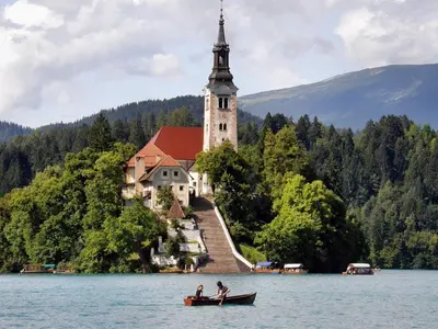 two people in a boat in the water in front of a church at Apartmaji Nena in Ročinj