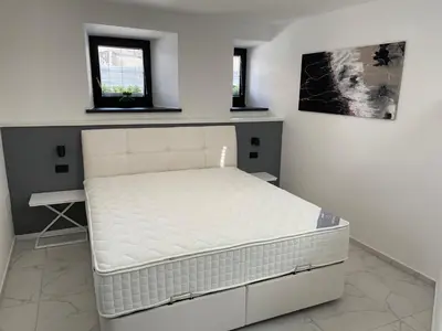 a white bed in a room with two windows at Apartment Aria in Kobarid