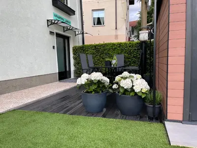 a patio with three pots of flowers and a bench at Apartment Aria in Kobarid