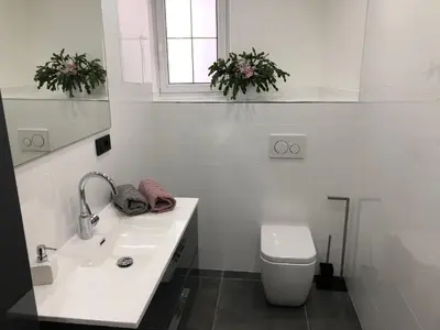 a white bathroom with a sink and a toilet at Apartment Aria in Kobarid