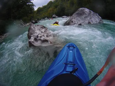 a person in a blue kayak on a river at Hostel X Point in Kobarid