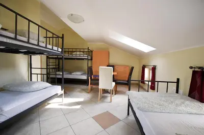 a room with three bunk beds and a table and chairs at Hostel X Point in Kobarid