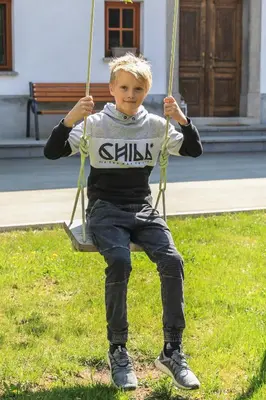 a young boy is sitting on a swing at Apartmaji Tina in Zgornje Gorje