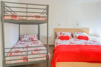 a bedroom with two bunk beds and a red bed at Apartmaji Tina in Zgornje Gorje