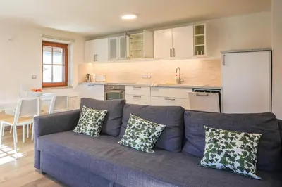 a living room with a blue couch and a kitchen at Apartmaji Tina in Zgornje Gorje