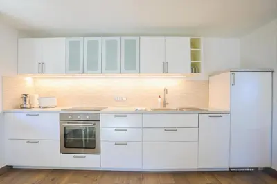 a white kitchen with white cabinets and a refrigerator at Apartmaji Tina in Zgornje Gorje