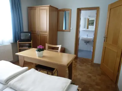 a room with a table and a bathroom with a sink at Motel Divjak in Spodnje Hoče