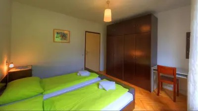 a bedroom with a green bed with a desk and a chair at Guesthouse Marko in Bled
