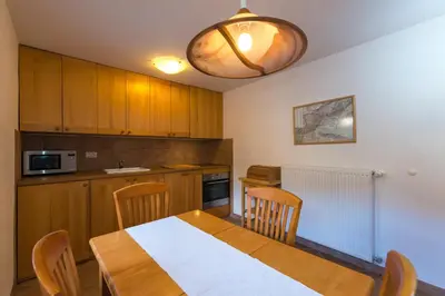 a kitchen with a wooden table with chairs and a light at Koritnica Apartments in Bovec