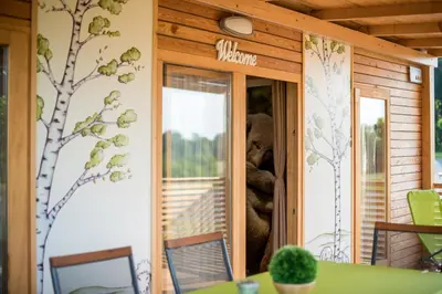 a teddy bear sitting in the window of a house at Glamping Krone Kolpa Heaven in Adlešiči