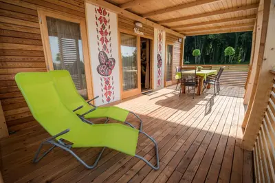 a wooden deck with a green chair and a table at Glamping Krone Kolpa Heaven in Adlešiči