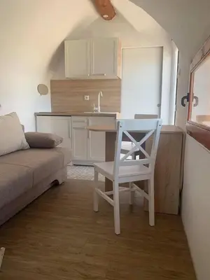 a small kitchen with a table and a white chair in a room at Glamping Krone Kolpa Heaven in Adlešiči