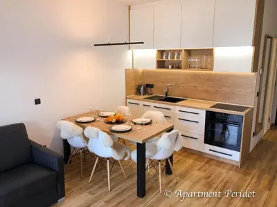 a kitchen with a table with white chairs and a sink at Villa Mojca - Apartment Peridot in the Center with Private Indoor Parking in Kranjska Gora