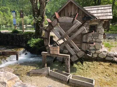 a wooden watermill sitting in front of a waterfall at Villa Mojca - Apartment Peridot in the Center with Private Indoor Parking in Kranjska Gora