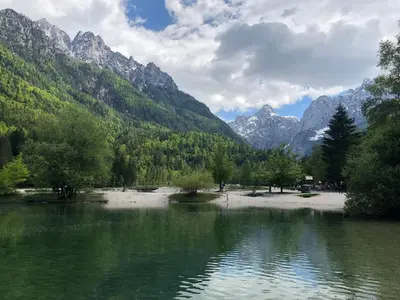 a lake with trees and mountains in the background at Villa Mojca - Apartment Peridot in the Center with Private Indoor Parking in Kranjska Gora
