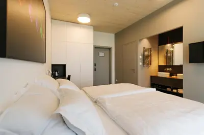 two white beds in a room with a tv on the wall at WUD hotel in Ljubljana