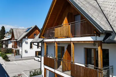 an apartment building with wooden balconies and a parking lot at Deluxe apartments Bled in Bled