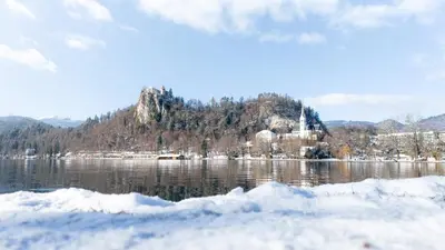 an island in the middle of a lake with snow at Deluxe apartments Bled in Bled