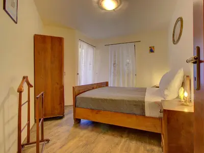 a bedroom with a bed and a wooden floor at Family Apartment Rihter in Črni Kal