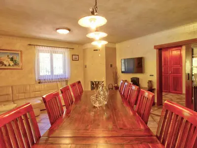 a dining room with a long wooden table and chairs at Family Apartment Rihter in Črni Kal