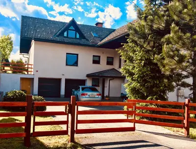 a house with a fence in front of a car at Stay Apartments Bled in Bled