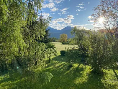 a garden with trees and mountains in the background at Stay Apartments Bled in Bled