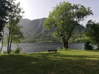 a park bench sitting in the grass near a lake at Apartment Ana in Bohinj