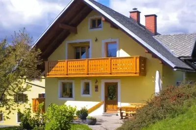 a large yellow house with a wooden balcony at APARTMA PR TAVČARJU in Zgornje Gorje