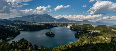 an island in the middle of a lake with mountains at APARTMA PR TAVČARJU in Zgornje Gorje