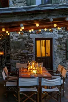 a wooden table with chairs and a stone building at Klavze 28 in Most na Soči