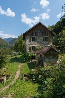 an old stone house on a hill with a dirt road at Klavze 28 in Most na Soči