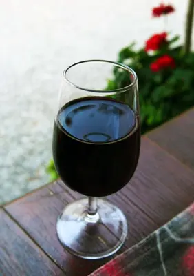 a glass of red wine sitting on a wooden table at Apartmaji pri Živcovih in Dutovlje