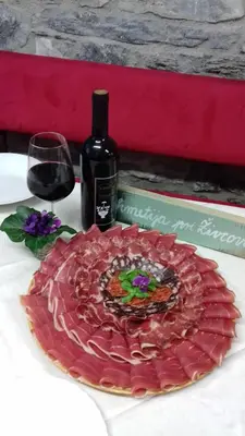 a table with a wine bottle and a plate of meat at Apartmaji pri Živcovih in Dutovlje