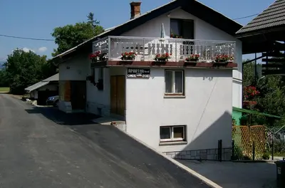 a white house with a balcony with flowers on it at Guest House Ivanka in Bled