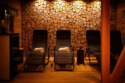 a room with three chairs and a wall of logs at Alpine Homestead in Goreljek